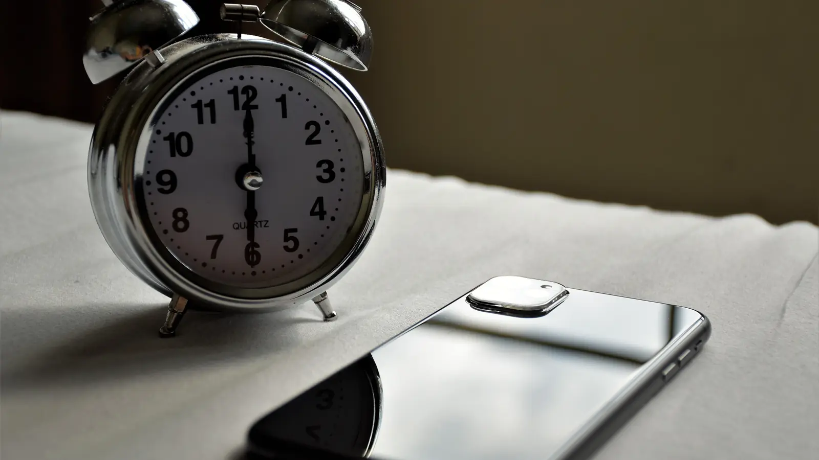 Alarm clock next to a smartphone, waiting for loan funds to arrive