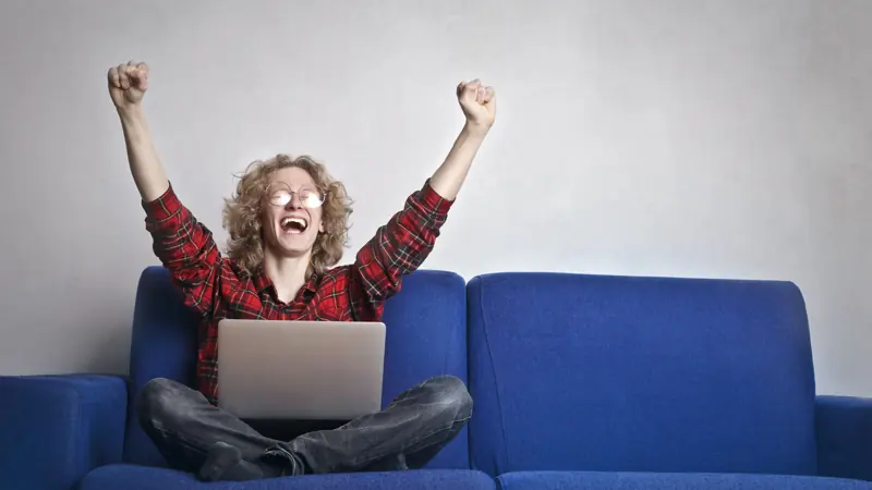 Excited person celebrating in front of a laptop after paying off a loan