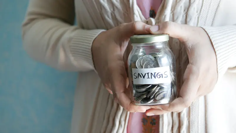 Hands holding a savings jar filled with coins