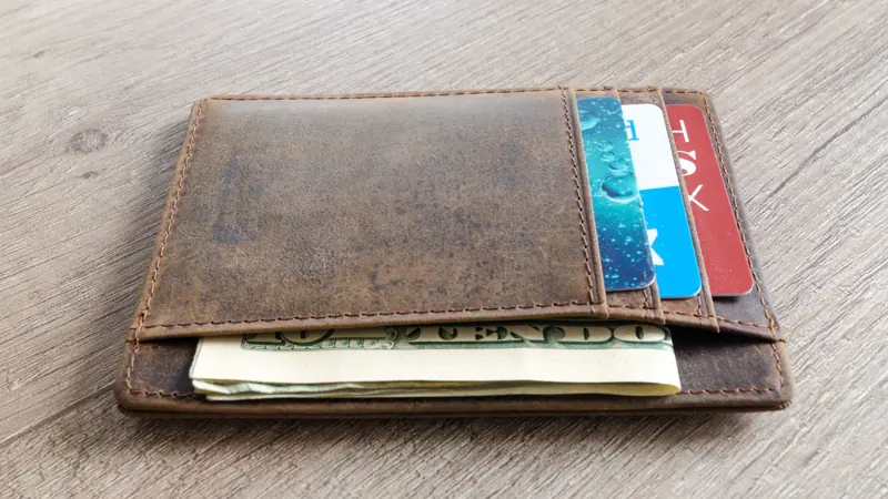 Leather wallet holding cash and cards on a table